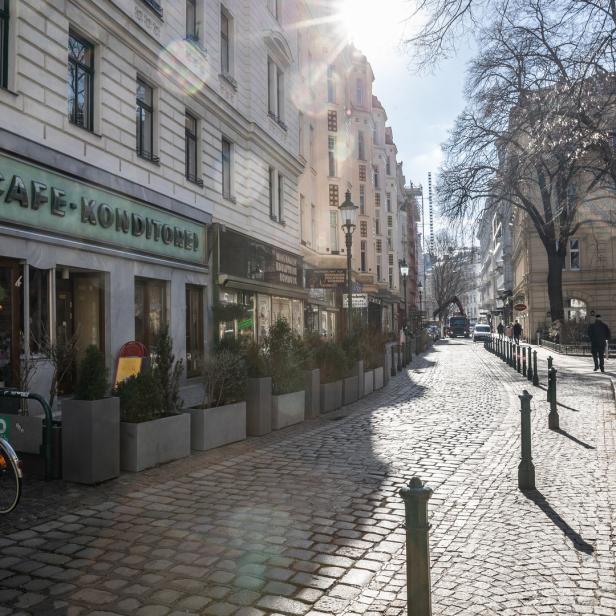 Eine Kopfsteinpflasterstraße mit einem Café und Geschäften an einem sonnigen Tag.