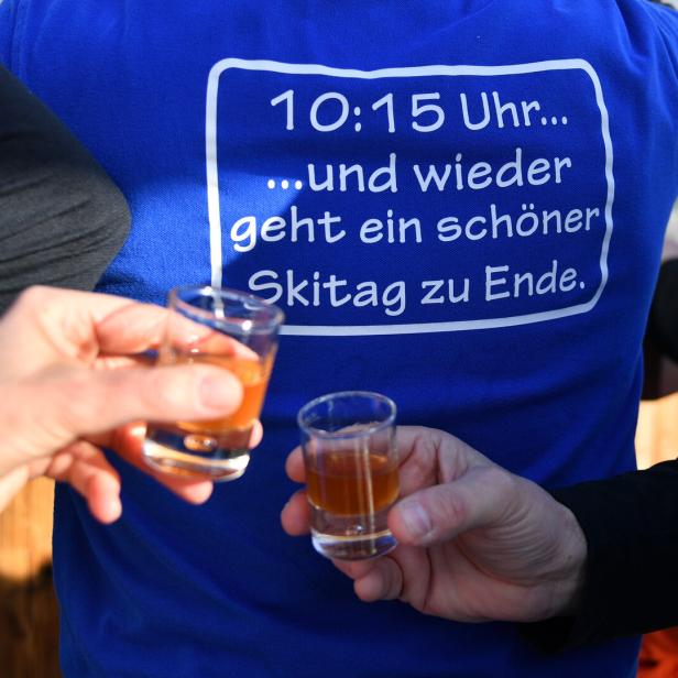 Zwei Personen stoßen mit Schnapsgläsern vor dem Aufdruck „10:15 Uhr… und wieder geht ein schöner Skitag zu Ende“ an.