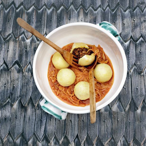 Grammelknödel mit Kraut und zwei Holzlöffeln in einer Schüssel.