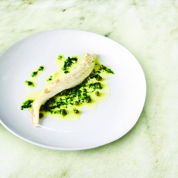 Ein Teller mit Fisch, garniert mit Kräutern und Kapern.