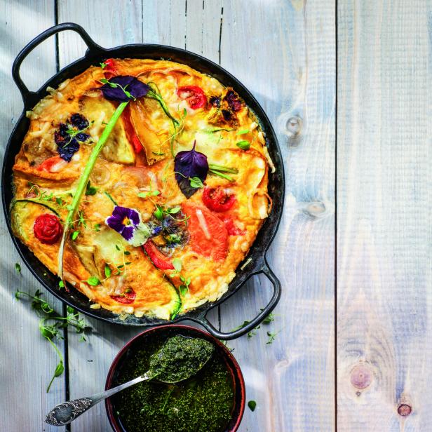 Eine Gemüsetortilla in einer gusseisernen Pfanne mit Pesto auf einem Holztisch.