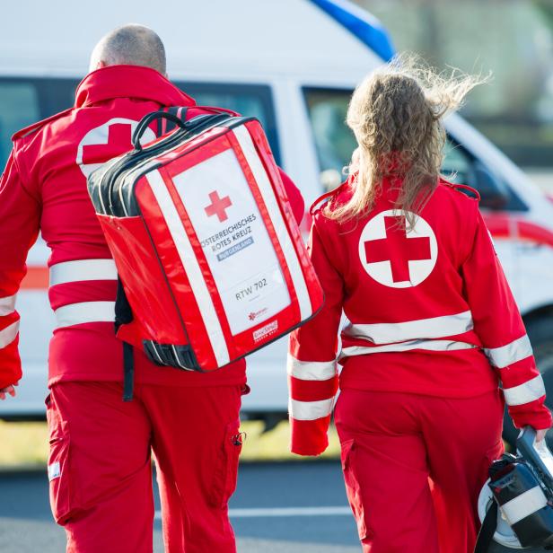 Zwei Sanitäter des Österreichischen Roten Kreuzes gehen zu einem Rettungswagen.