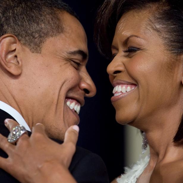 Barack und Michelle Obama lächeln sich an.