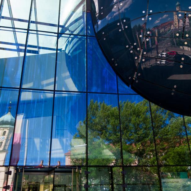 Die Spiegelung einer Stadtlandschaft in der Glasfassade eines Gebäudes.