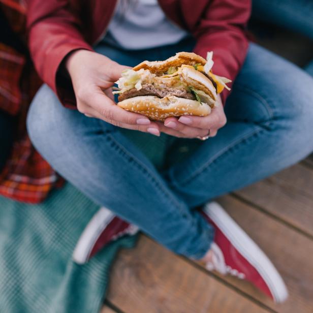 Eine Person hält einen angebissenen Hamburger in den Händen.