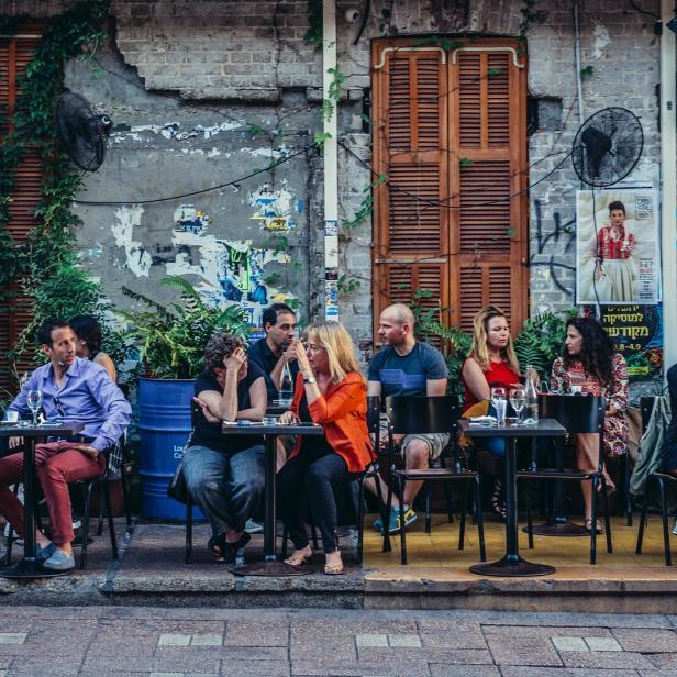 Menschen sitzen vor einem Restaurant in Tel Aviv.
