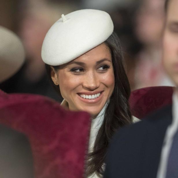 Herzogin Meghan lächelt mit einer weißen Baskenmütze.