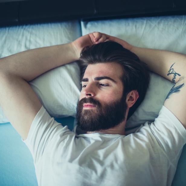 Porträt eines traurigen, bärtigen Mannes, der im Bett liegt.