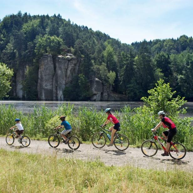Eine Gruppe von Radfahrern fährt auf einem Weg entlang eines Sees.