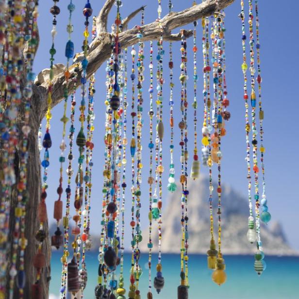 Ein Baum ist mit bunten Perlenketten am Strand geschmückt.