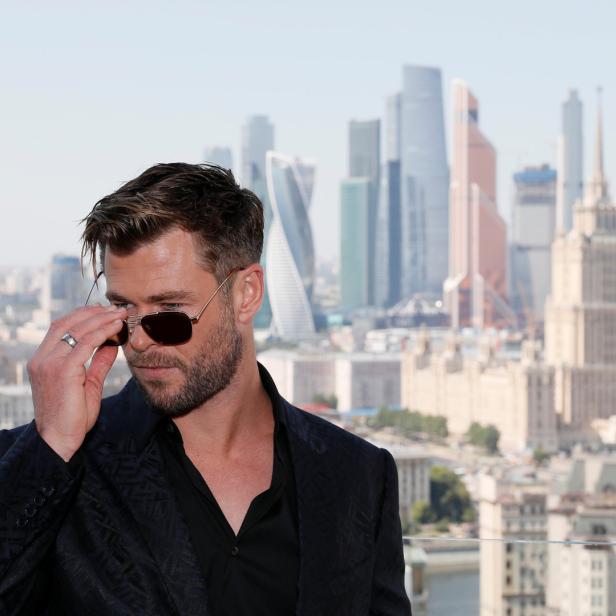 Chris Hemsworth posiert mit Sonnenbrille vor der Skyline von Moskau.