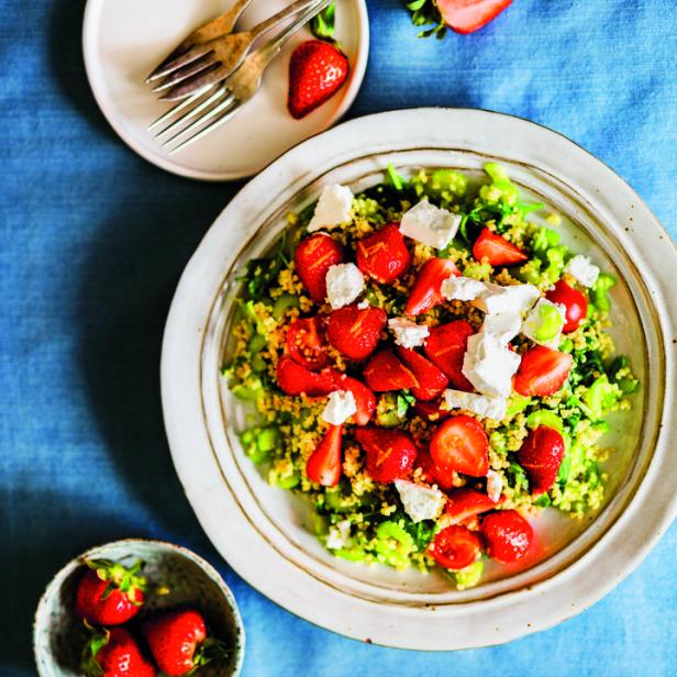 Ein Teller mit Erdbeersalat und Feta-Käse auf einem blauen Tuch.