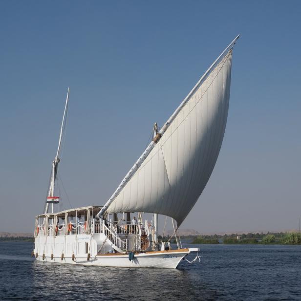 Eine weiße Feluke segelt auf dem Nil.