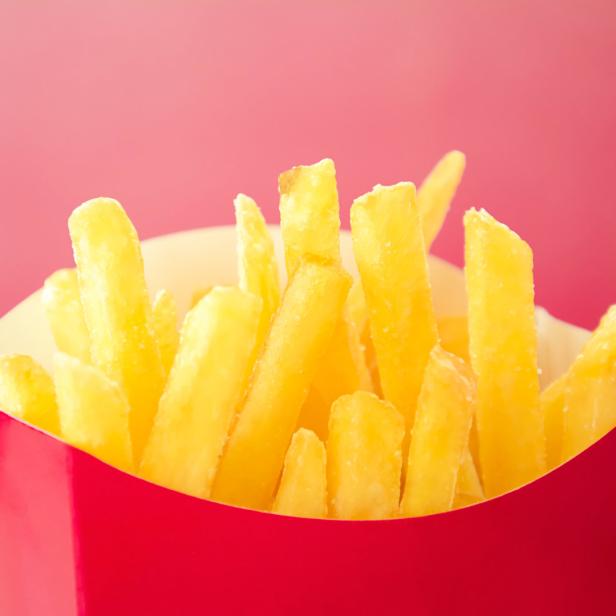 Eine rote Pappschachtel ist gefüllt mit goldgelben Pommes Frites.