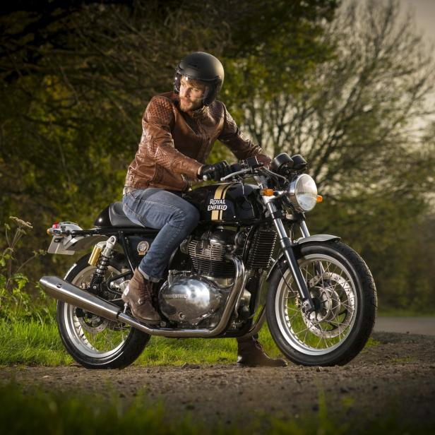 Ein Mann mit Lederjacke und Helm sitzt auf einem Royal Enfield Motorrad.