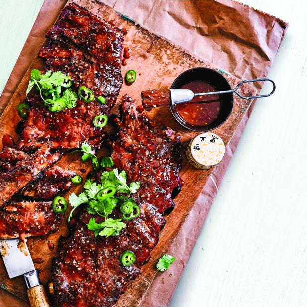 Spareribs mit Glasur, Koriander und Jalapeños auf einem Holzbrett.