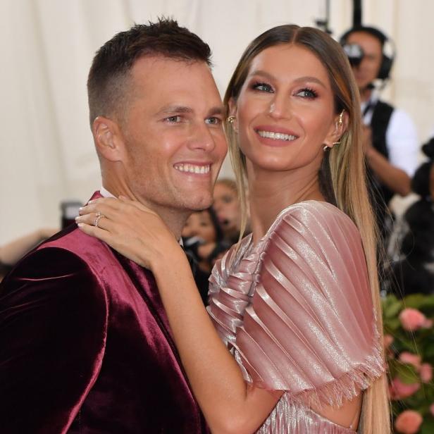 Tom Brady und Gisele Bündchen posieren lächelnd auf einem roten Teppich.