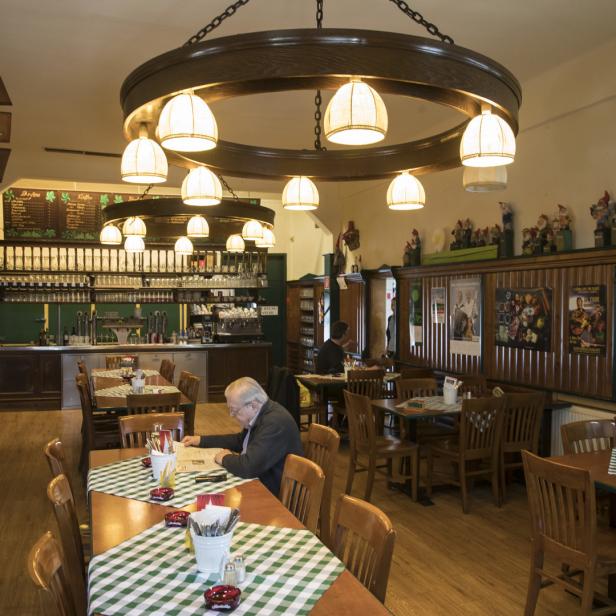 Ein Mann liest in einem traditionellen deutschen Restaurant die Zeitung.