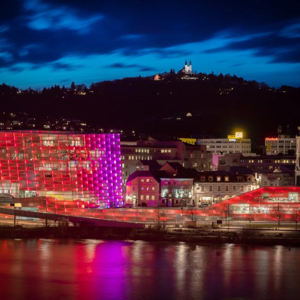 Blick auf Linz bei Nacht mit dem Ars Electronica Center und dem Pöstlingberg im Hintergrund.