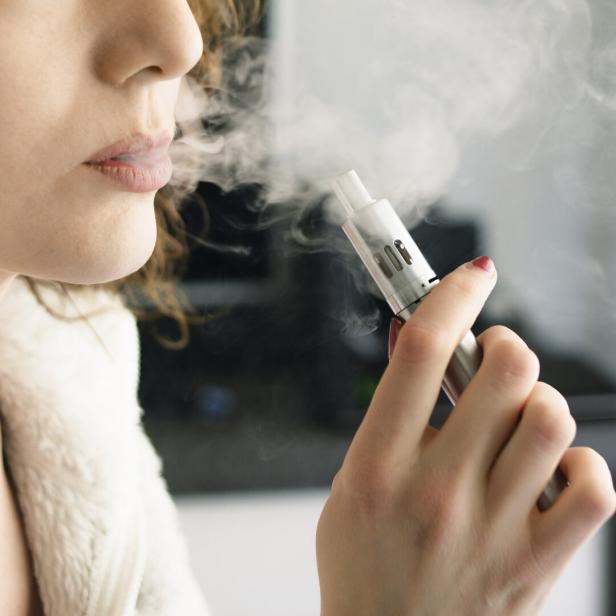 Eine junge frau raucht eine E-Zigarette.