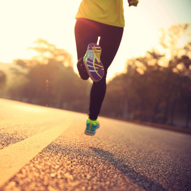 Eine Person joggt auf einer asphaltierten Straße in Richtung Horizont.