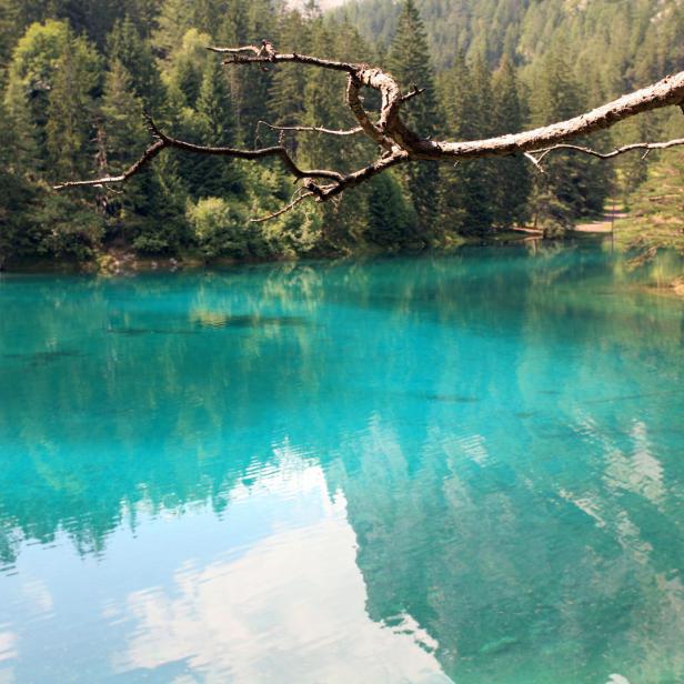 Türkisblaues Wasser spiegelt den Himmel und die umliegenden Bäume wider.