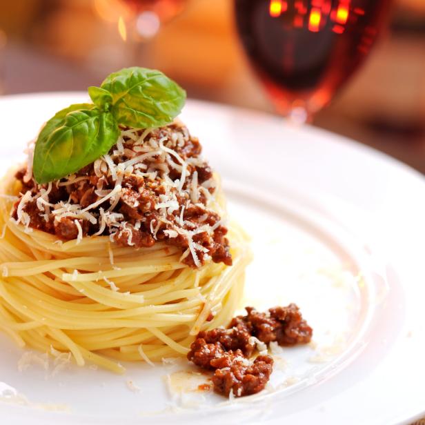 Ein Teller Spaghetti Bolognese mit Basilikum und geriebenem Käse garniert.