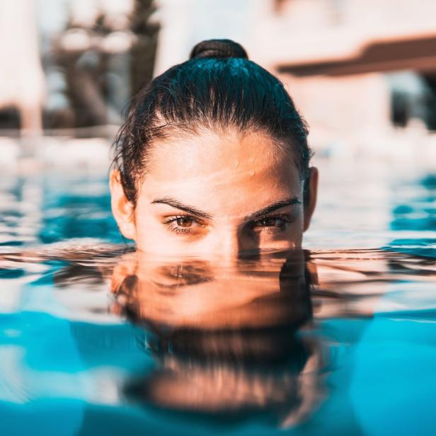 Eine Frau taucht bis zum Hals in blaues Wasser ein.