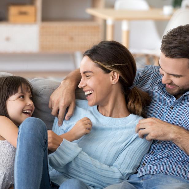 Eine glückliche Familie sitzt zusammen auf einem Sofa und lacht.