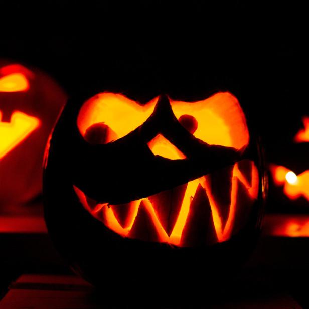 Drei geschnitzte Halloween-Kürbisse leuchten im Dunkeln.