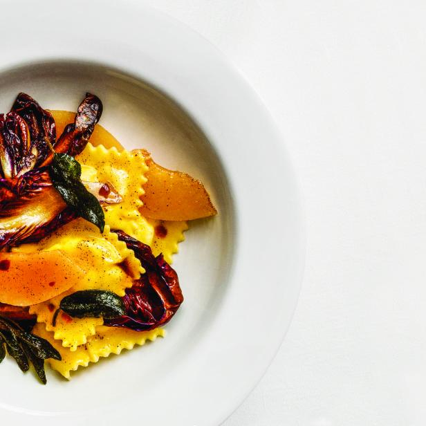 Ein Teller mit gelben Ravioli, Radicchio und Salbei auf einem weißen Teller.