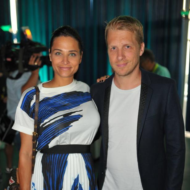 Eine Frau in einem blau-weiß gemusterten Kleid posiert mit einem Mann im Blazer für ein Foto.