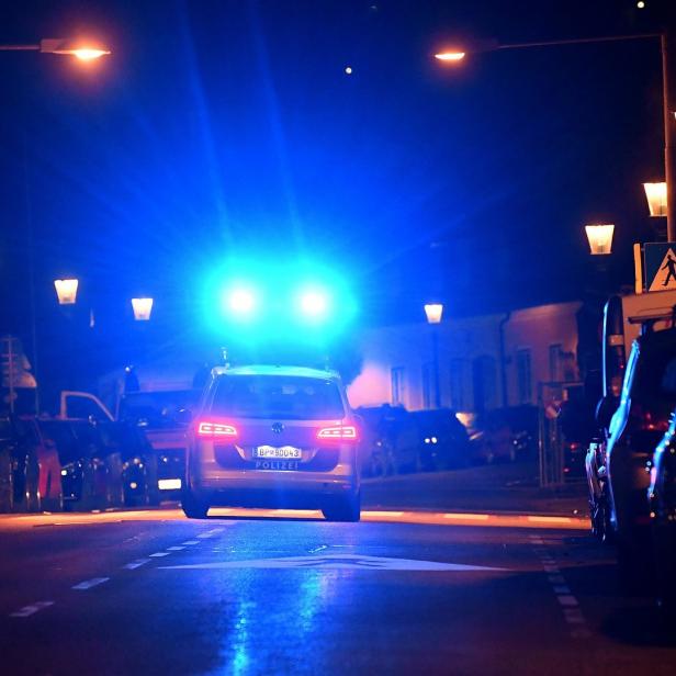 Ein Polizeiauto steht nachts mit eingeschaltetem Blaulicht auf einer Straße.
