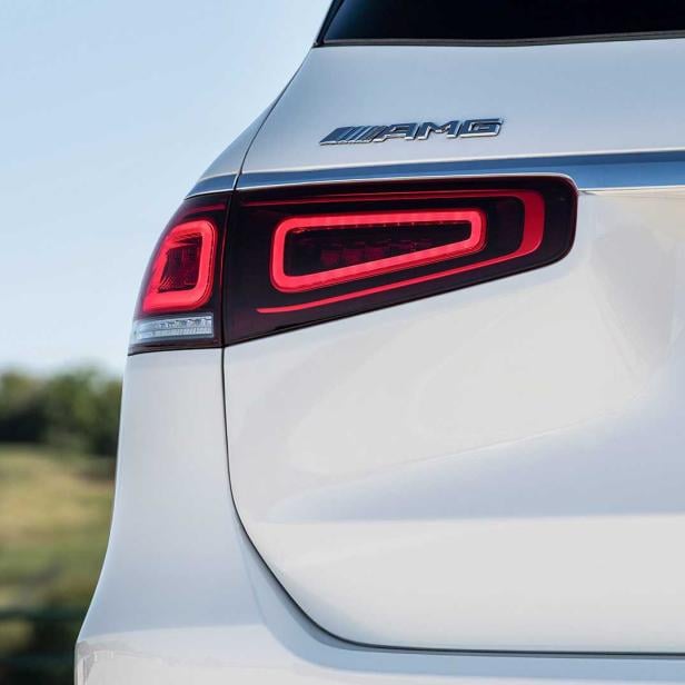 Detailansicht des Rücklichts und des AMG-Logos eines weißen Autos.