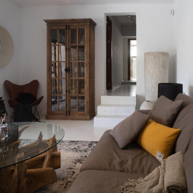 Ein Wohnzimmer mit einem braunen Sofa, einem Holztisch und einem Vitrinenschrank.