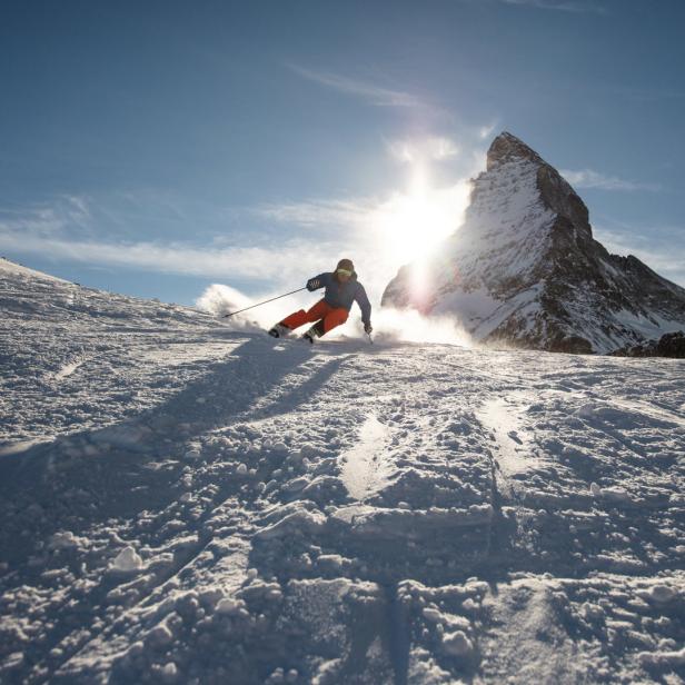 Ein Skifahrer fährt vor dem Matterhorn einen Hang hinunter.