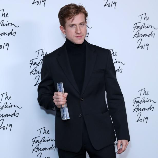 Ein Mann im schwarzen Anzug hält eine Auszeichnung der „Fashion Awards 2019“.
