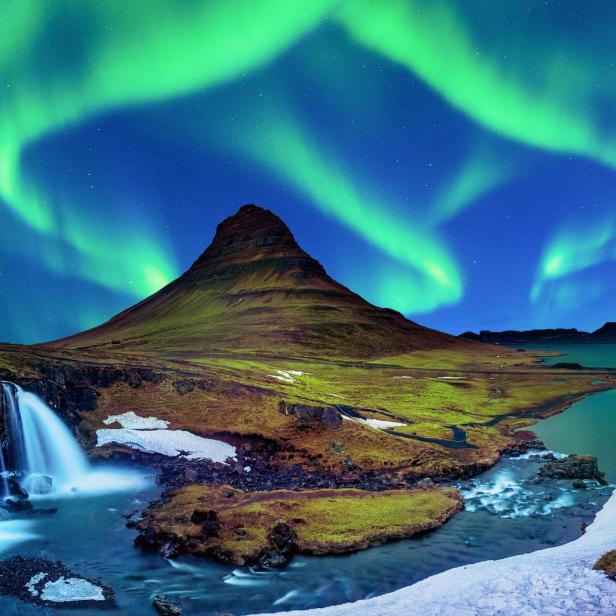 Nordlichter über dem Kirkjufell Berg und Wasserfall in Island.