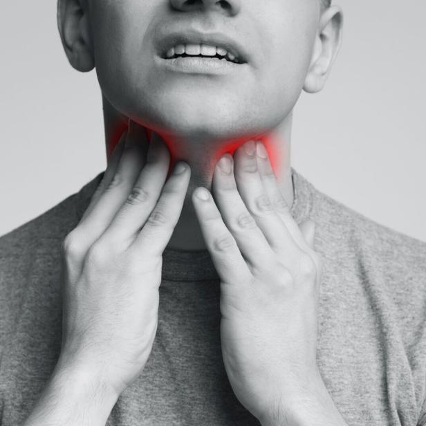 Man with thyroid gland problem, touching his neck