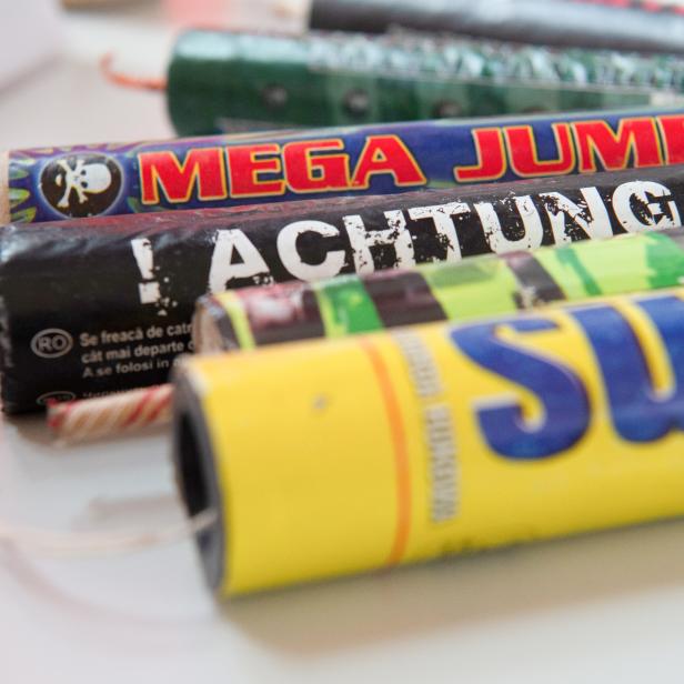Mehrere Feuerwerkskörper mit Aufschriften wie „Mega Jumbo“ und „Achtung!“ liegen auf einem Tisch.