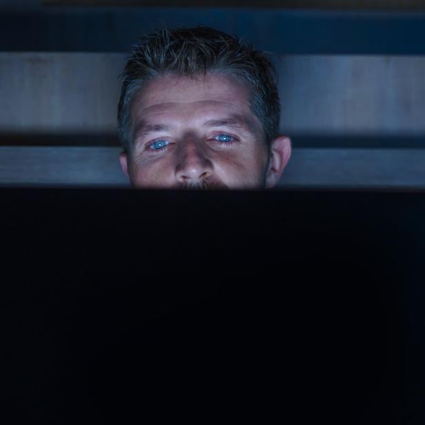 young attractive and relaxed internet addict man networking concentrated late at night on bed with laptop computer in social media addiction or workaholic businessman concept