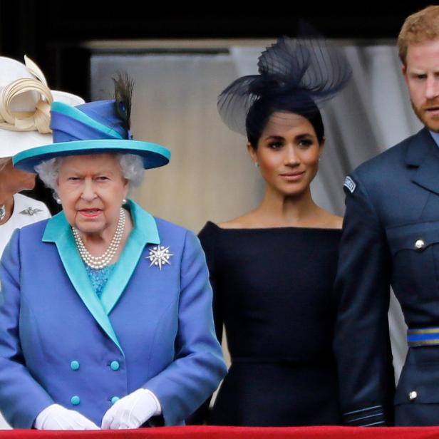 Königin Elisabeth II., Meghan Markle und Prinz Harry auf einem Balkon.