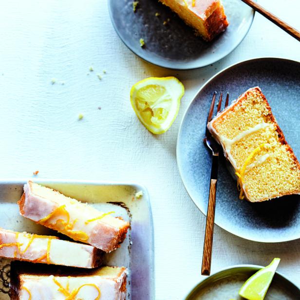 Ein Zitronenkuchen mit Zuckerguss und Zitronenzesten wird auf Tellern serviert.