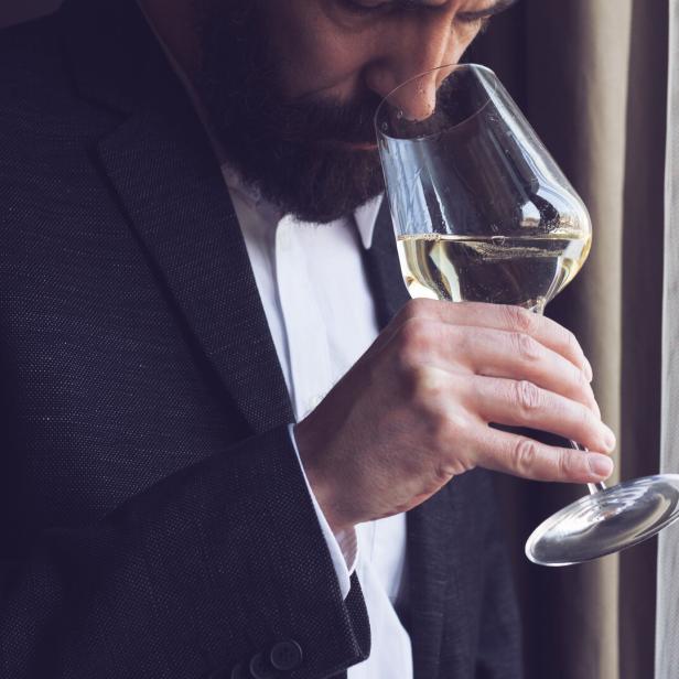 Ein Mann kostet Weißwein aus einem Weinglas