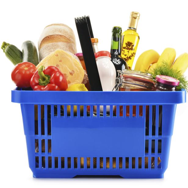 Shopping basket with variety of grocery products isolated on white
