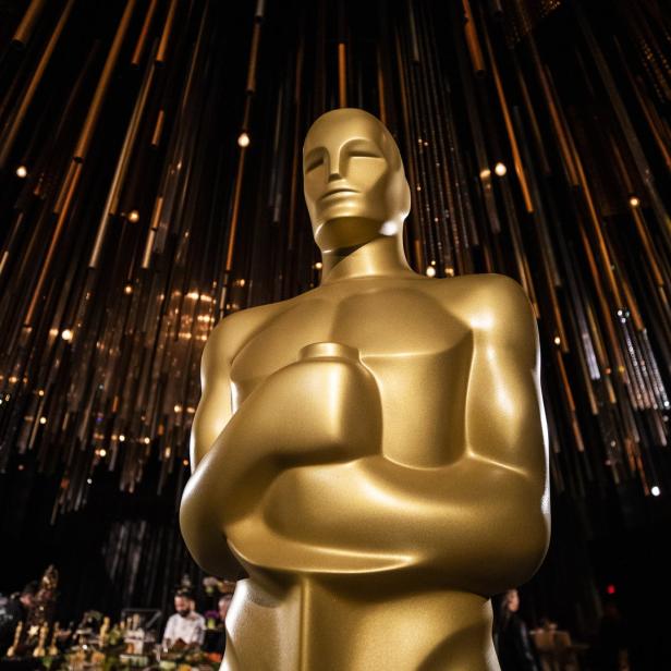 Eine goldene Oscar-Statue vor einem dunklen Hintergrund mit Lichteffekten.