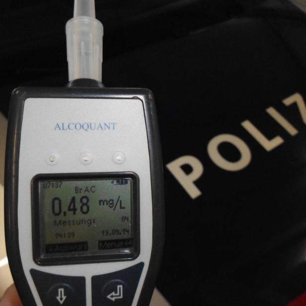 Ein Alcoquant-Alkoholtester zeigt einen Wert von 0,48 mg/L vor einem Polizeiauto.