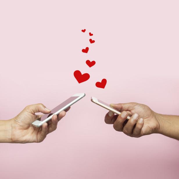 Zwei Hände halten Smartphones, aus denen rote Herzen aufsteigen.