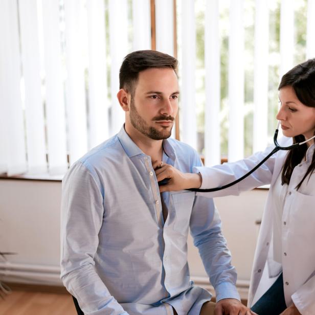 Eine Ärztin untersucht einen Patienten mit einem Stethoskop im Behandlungszimmer.