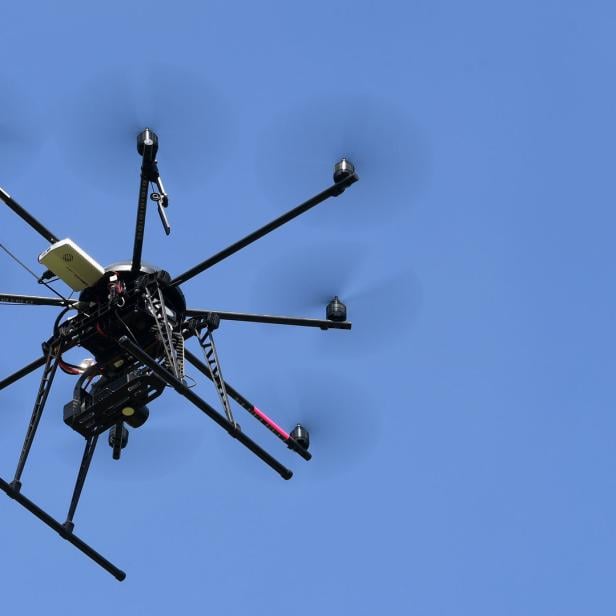 Zwei Drohnen fliegen vor blauem Himmel.
